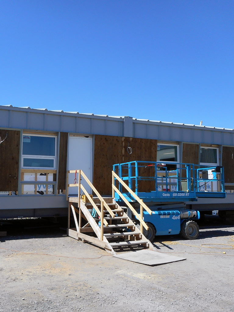 Grise Fiord 2 Modular daycare building on steel beams in Grise Fiord; temporary stairs and a blue scissor lift visible at the construction site.