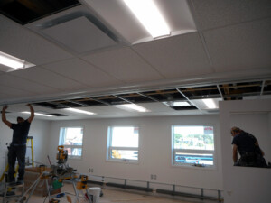 Workers installing a suspended ceiling inside Grise Fiord Learning & Childcare Facility classroom during interior fit-out.