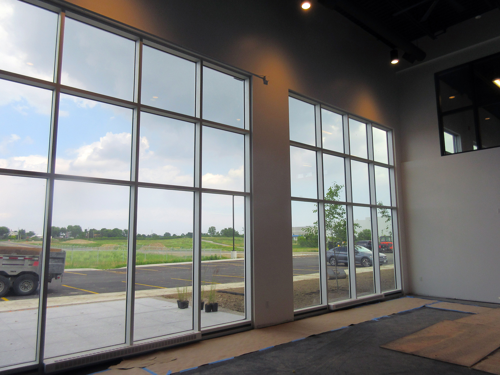 Latitude Air Ambulance 16 Interior view through two‑storey floor‑to‑ceiling windows at the Latitude Air Ambulance facility, overlooking a parking lot and grassy airfield.