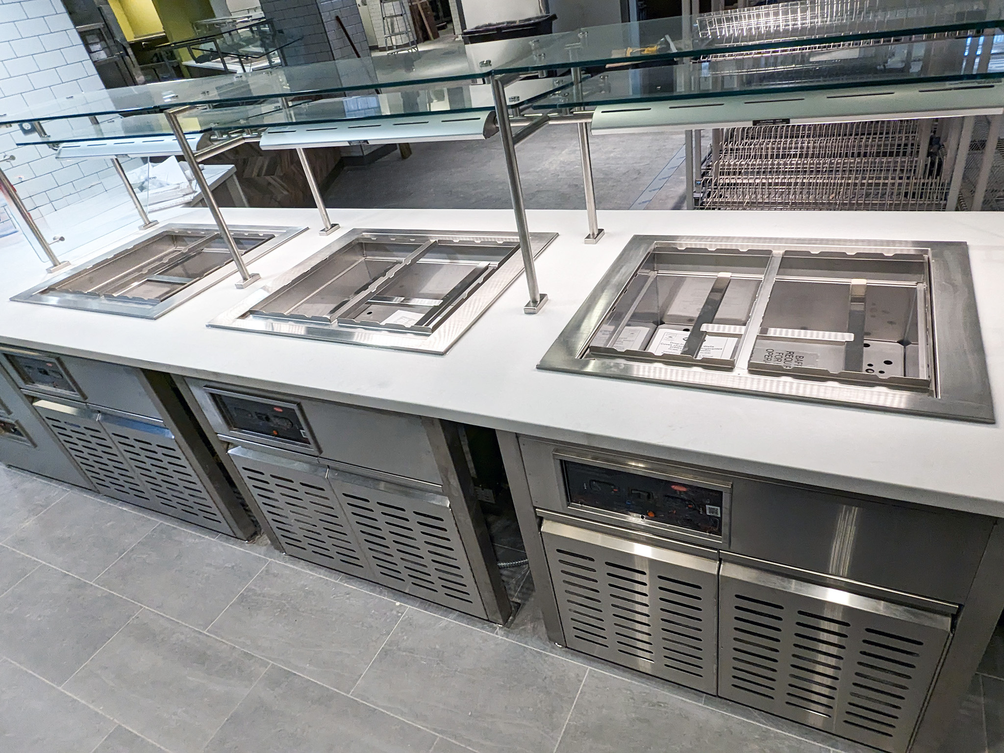 Leonard Hall 4 Close-up of stainless-steel refrigerated wells beneath a glass sneeze guard at Leonard Hall’s renovated food service counter.