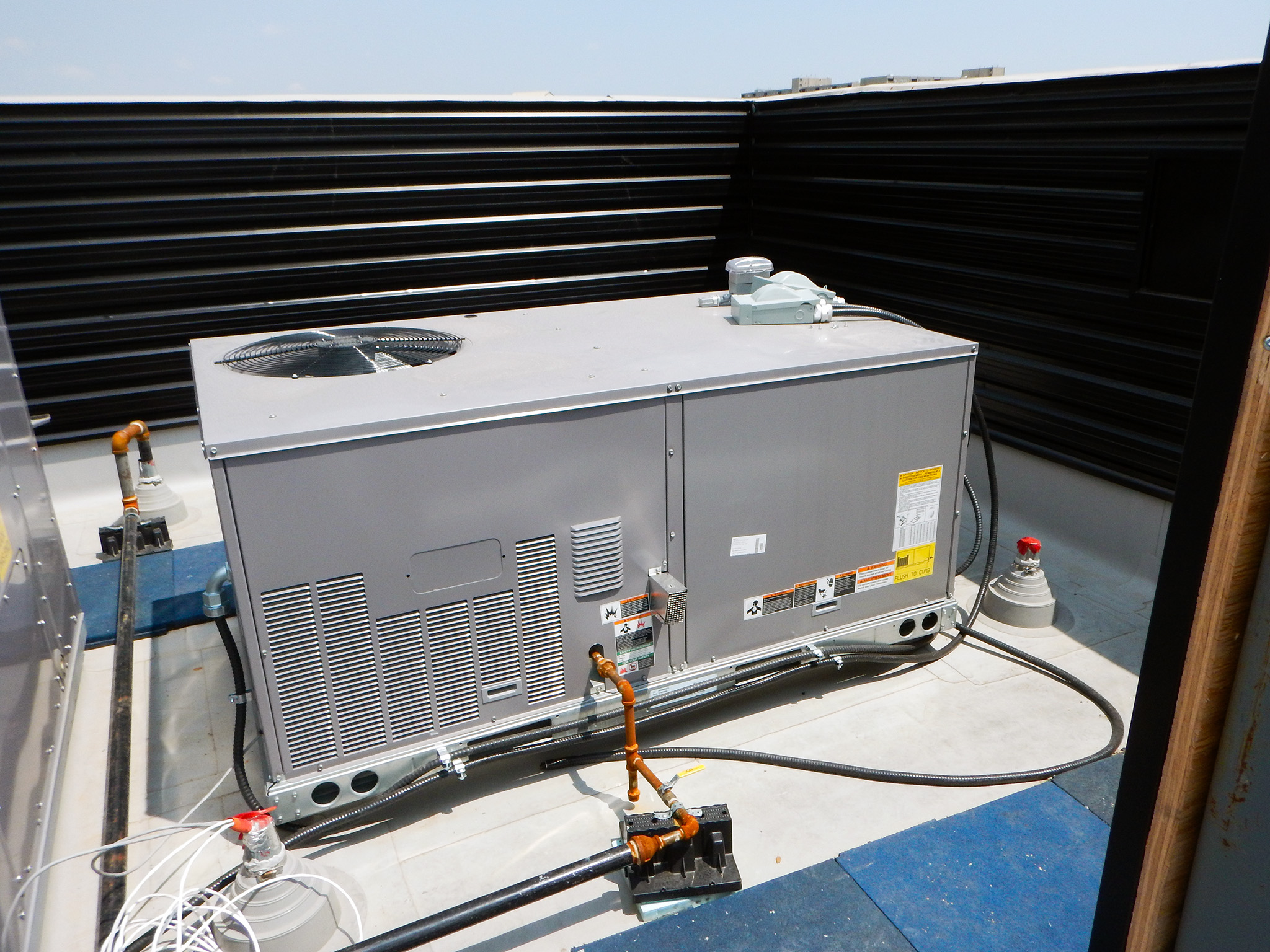 Nash Jewellers 15 Rooftop packaged HVAC unit installed on Nash Jewellers, showing connected electrical conduit and refrigerant piping within a low parapet enclosure.