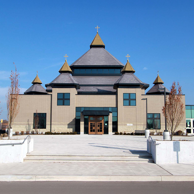 Front view of St. Joseph’s Ukrainian Catholic Church with gold-domed towers and a wide entrance under a clear blue sky.