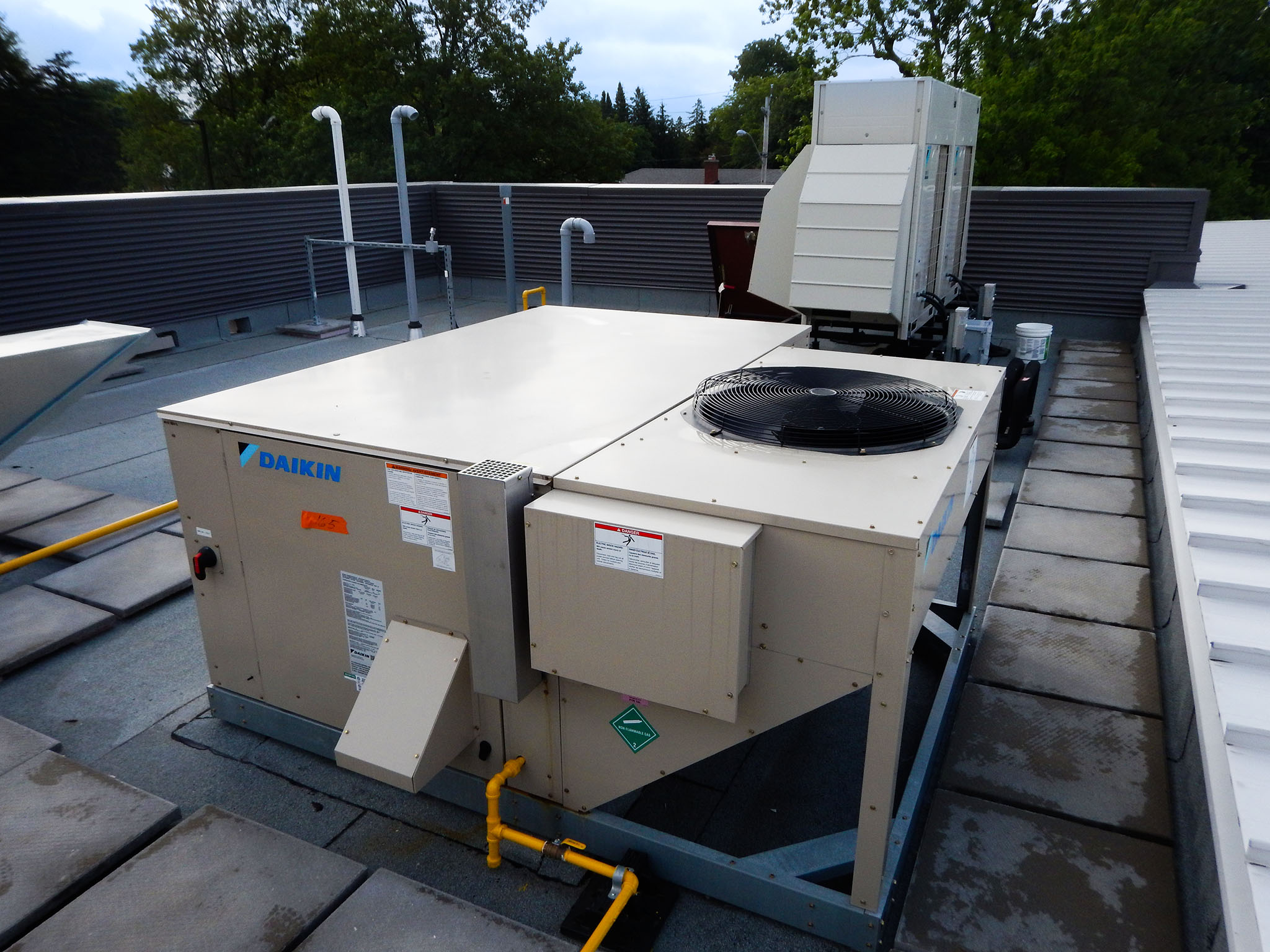 L'Arche 14 Rooftop Daikin HVAC unit with visible fan, duct connections, and gas piping at the L’Arche Gathering Facility.