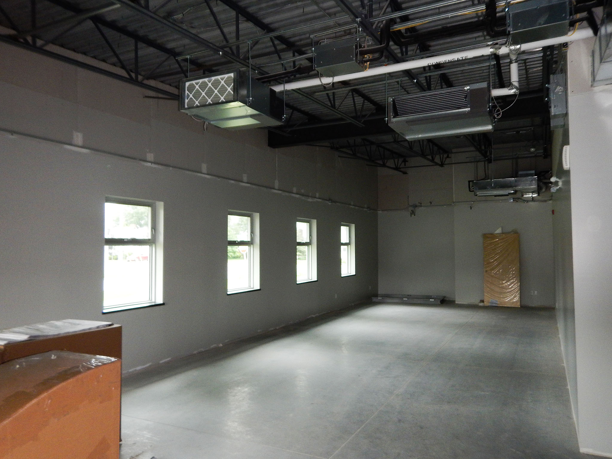L'Arche 3 Unfinished interior room at the L’Arche Gathering Facility with exposed ductwork and multiple windows.