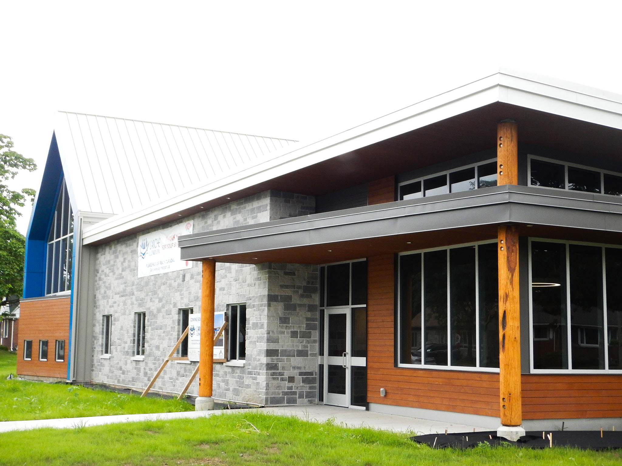 L'Arche 8 Exterior of the L’Arche Gathering Facility with stone and wood façade, tall windows, and timber columns at entrance.