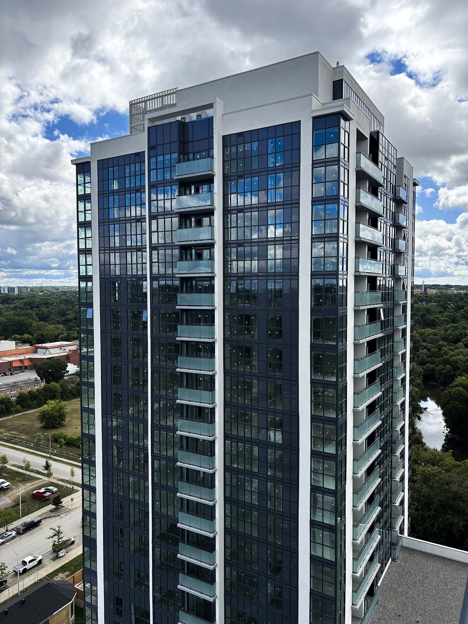 Close-up view of SOHOSQ’s glass-clad residential tower with balconies, set against a cloudy sky and river backdrop.