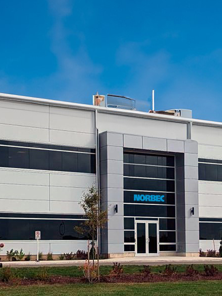 Norbec Exterior 2 Norbec’s Strathroy facility exterior with glass entry and light gray metal panel façade.