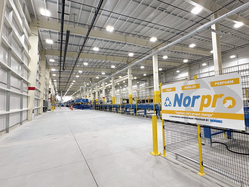 Norbec Industrial 8 Interior of Norbec’s Strathroy plant showing the production line with conveyors, overhead lighting, and a Norpro program sign in the foreground.