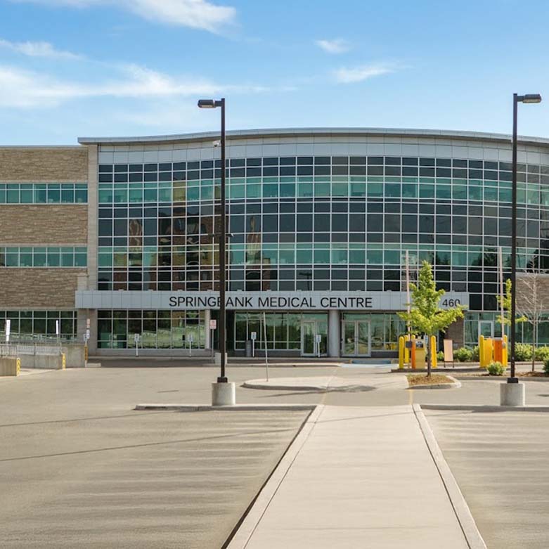 Springbank Medical Front view of the Springbank Medical Centre with a glass exterior and entrance facing the parking area.