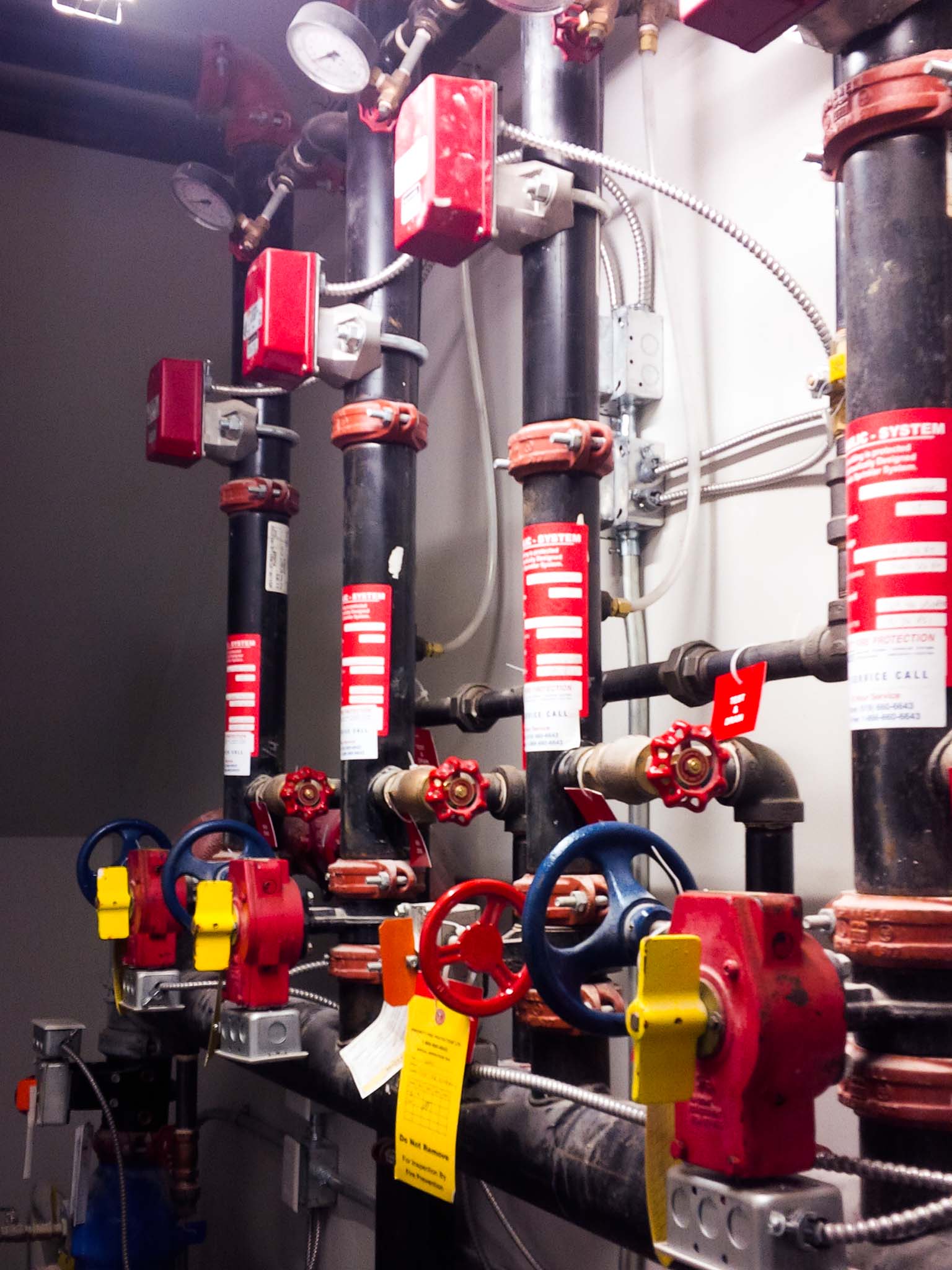 BMO Centre (11) Fire protection piping with gauges, valves, and red supervisory switches inside a mechanical room.