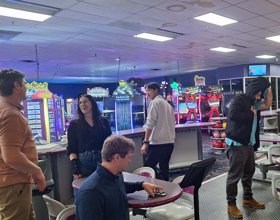 Team members gather at a bowling alley during a social event.
