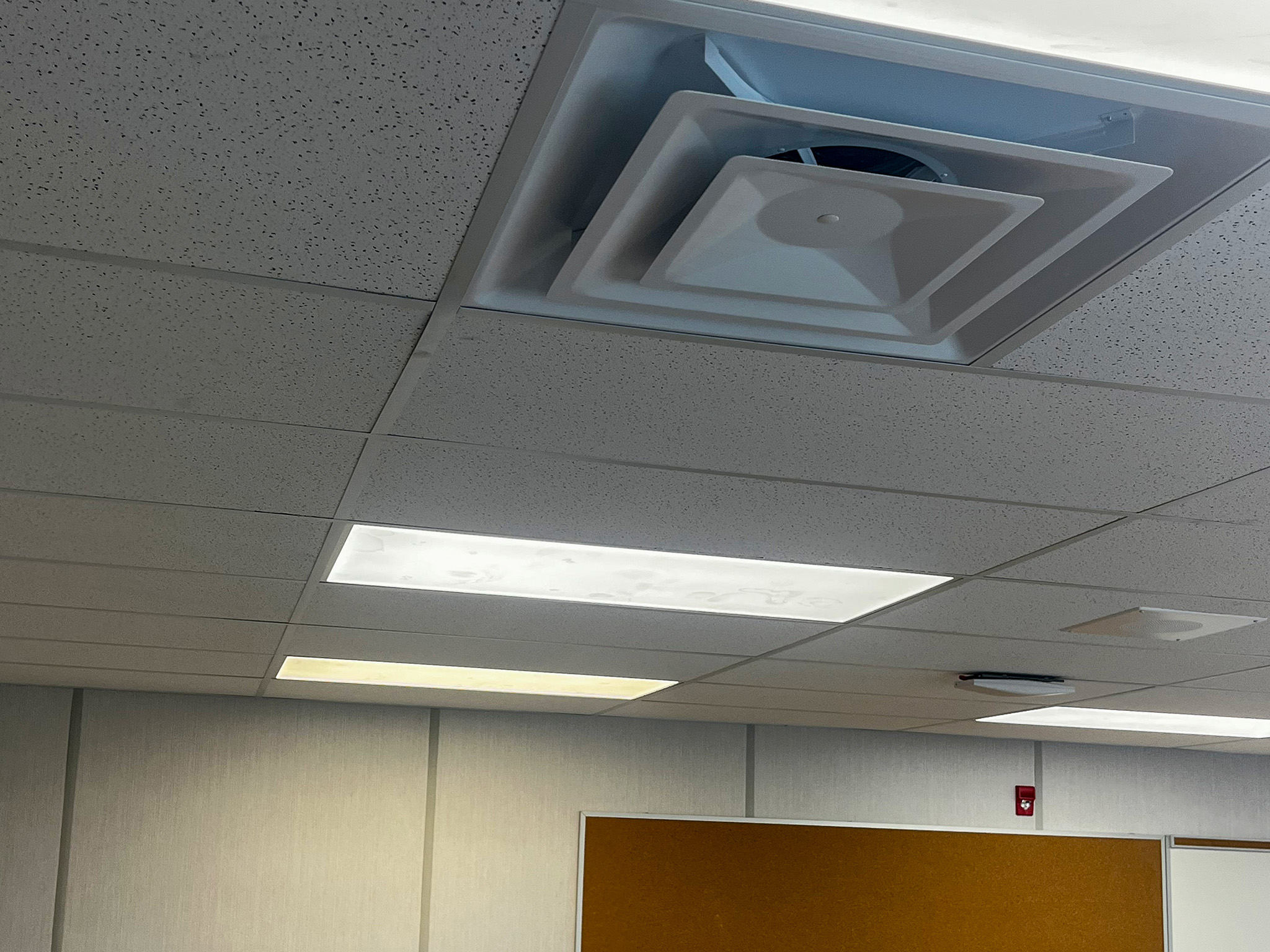 Beckwith Public School (2) Ceiling ventilation diffuser and rectangular light fixtures above a bulletin board inside a portable classroom.