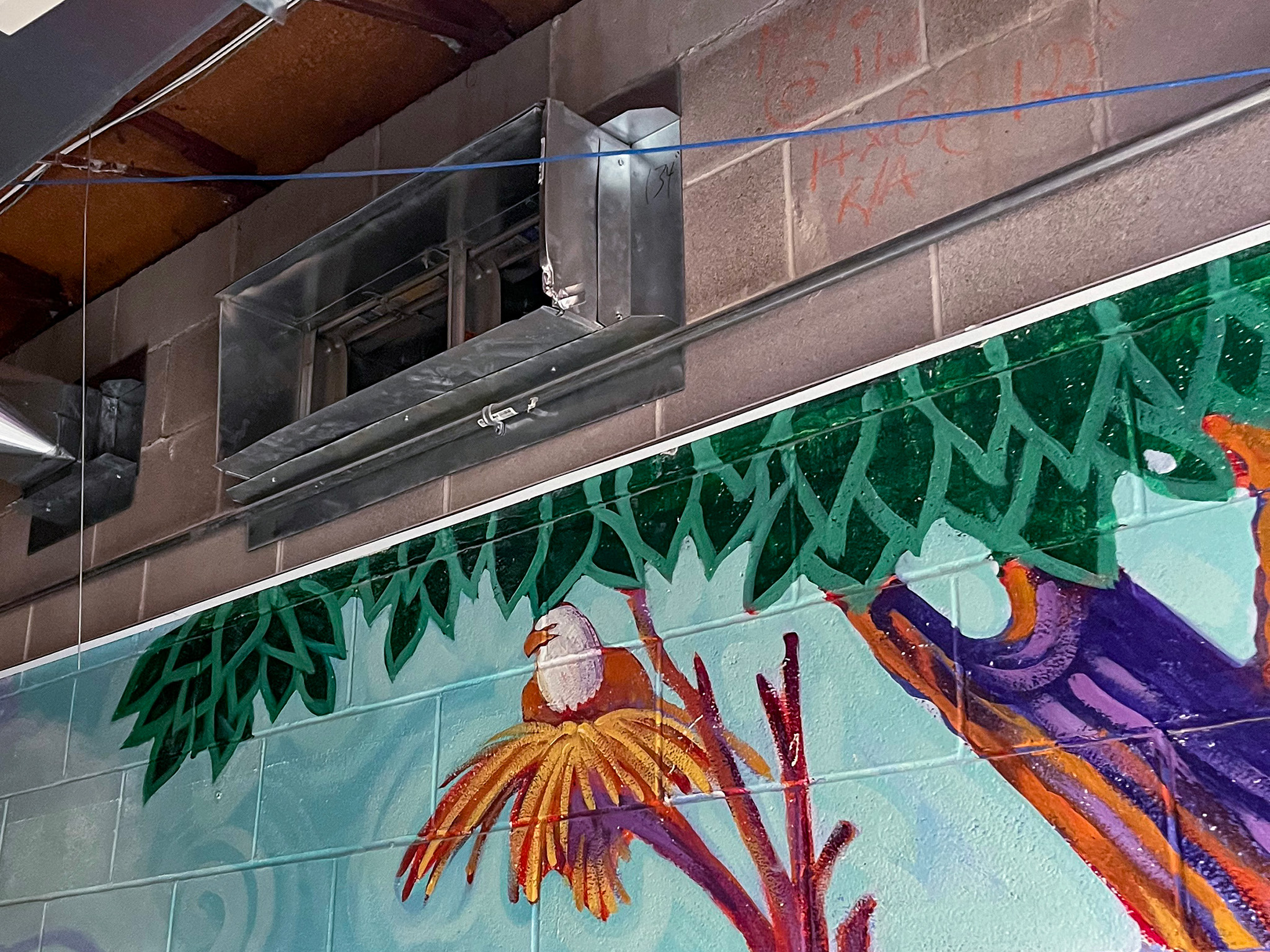 Elginburg Public School (4) Exposed metal ventilation ductwork above a colourful school mural depicting birds, branches, and foliage.