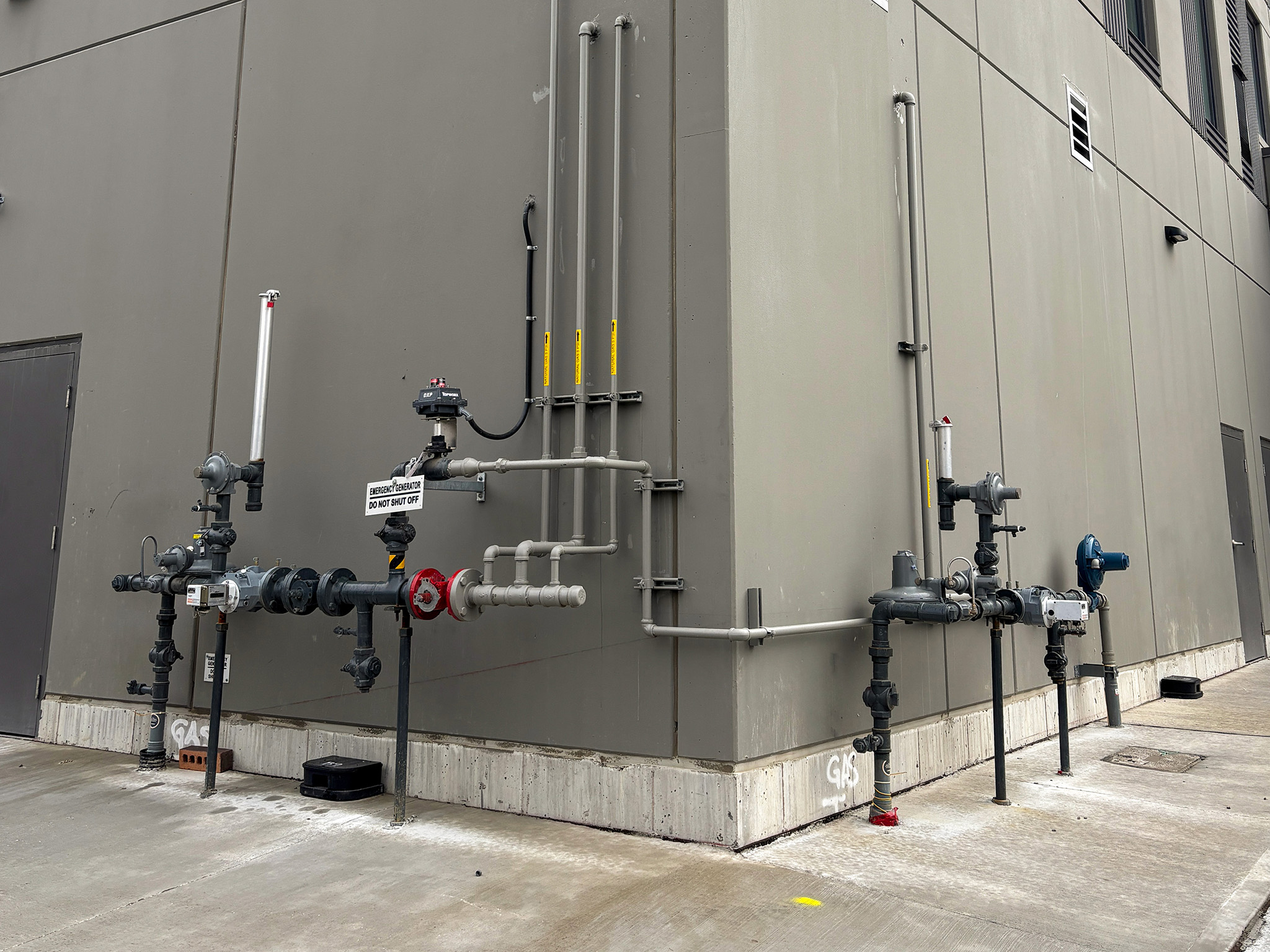 Rodzik Hall (4) Exterior building wall with exposed natural gas piping, meters, shutoff valves, and regulators.