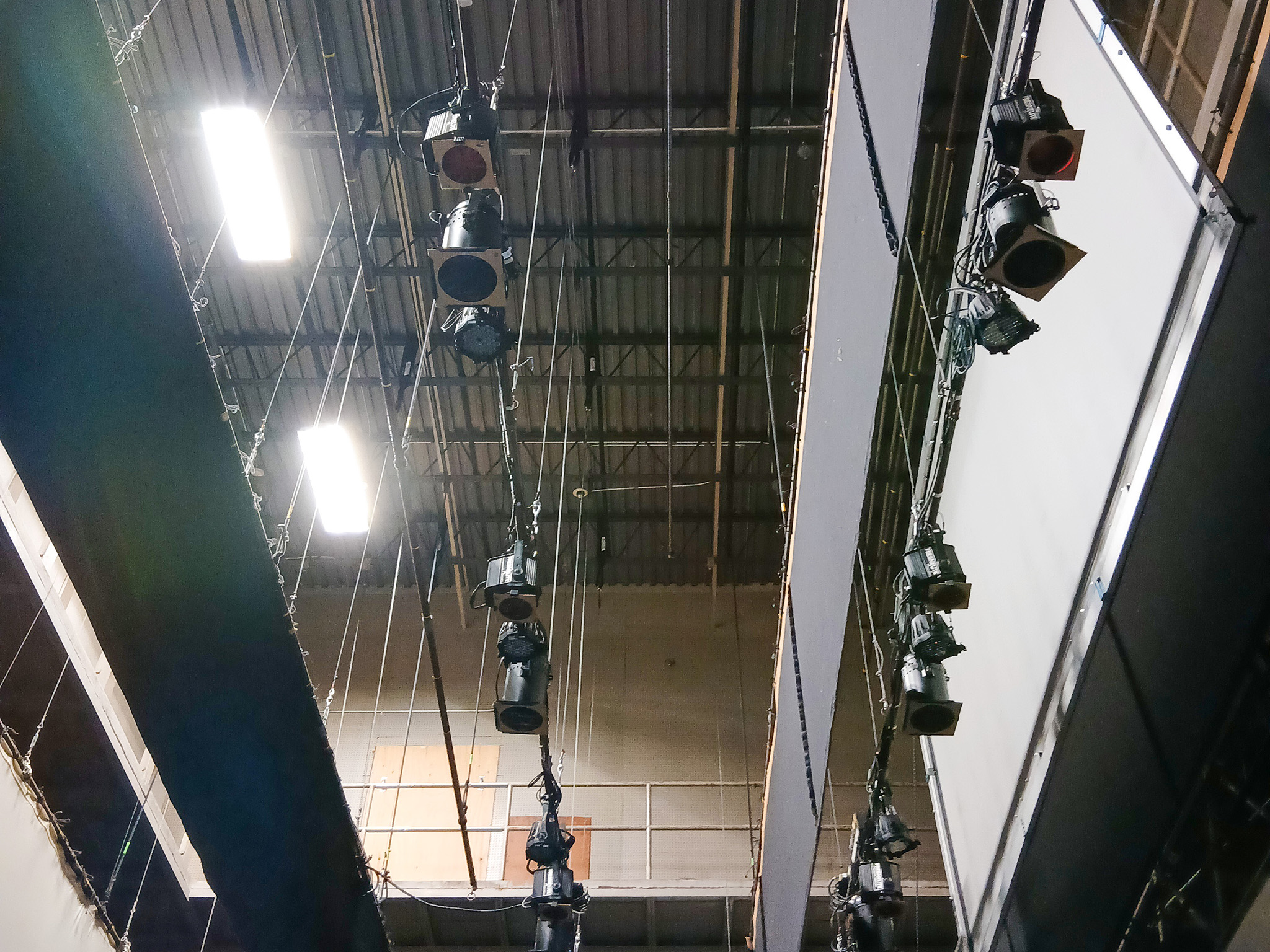 Wilfrid Laurier University Theatre Auditorium (3) Overhead view of theatrical lighting fixtures, suspended rigging, cables, and structural supports above the stage.