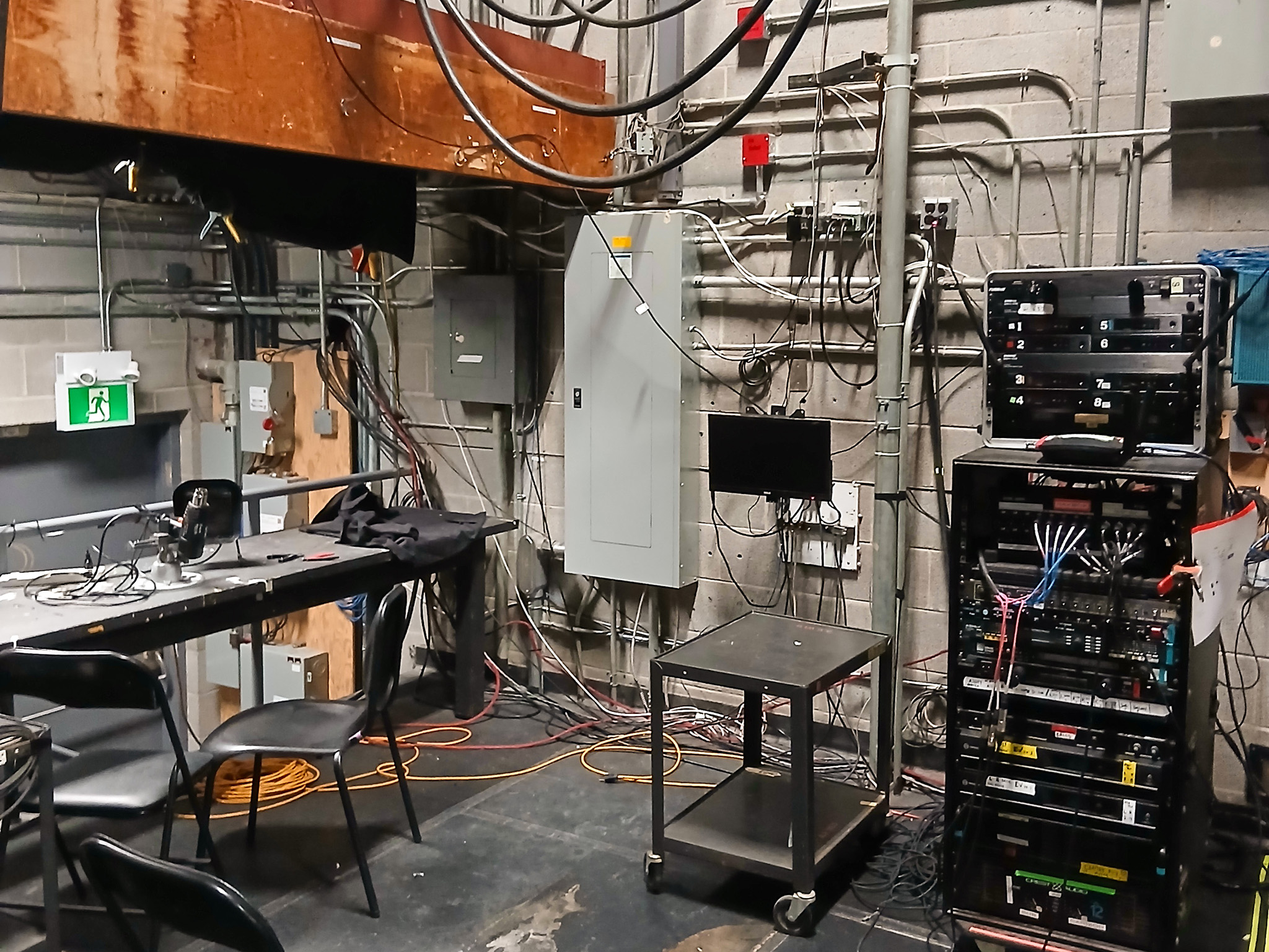 Wilfrid Laurier University Theatre Auditorium (4) Theatre control room containing electrical panels, equipment racks, monitors, exposed wiring, and workstations.